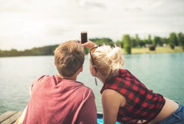 Un couple de jeunes gens prenant un selfie au bord d'un magnifique lac