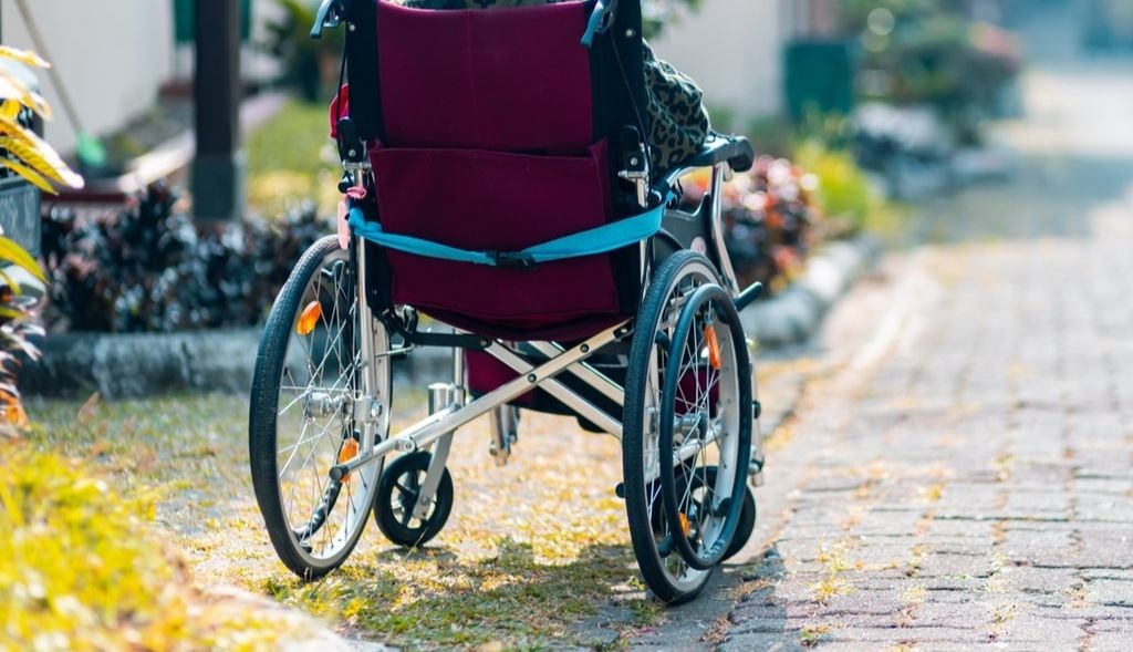 Une personne en fauteuil roulant dans une petite rue.