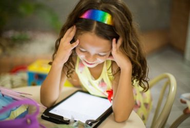 Une petite fille concentrée sur sa tablette.